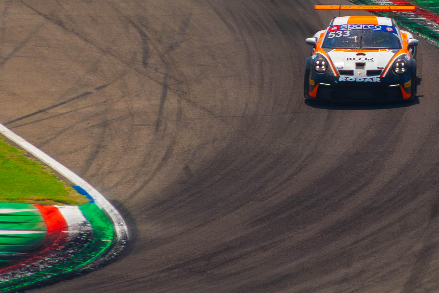 Front view of Porsche 911 GT3 Cup #533 entering a corner over kerbs at Imola Circuit