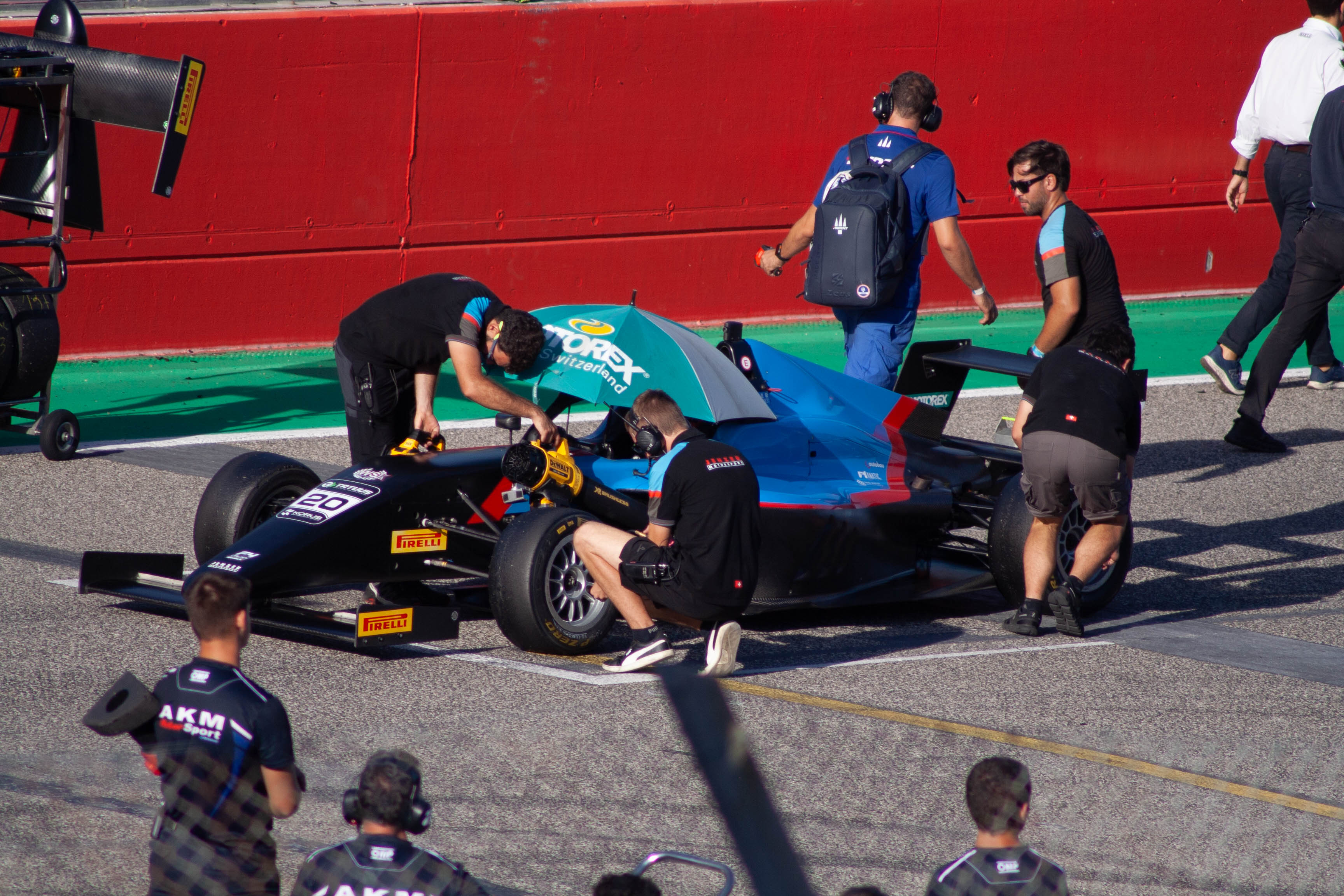 AKM Motorsport mechanics preparing a Formula 4 single-seater #20 on the pit grid at Imola Circuit