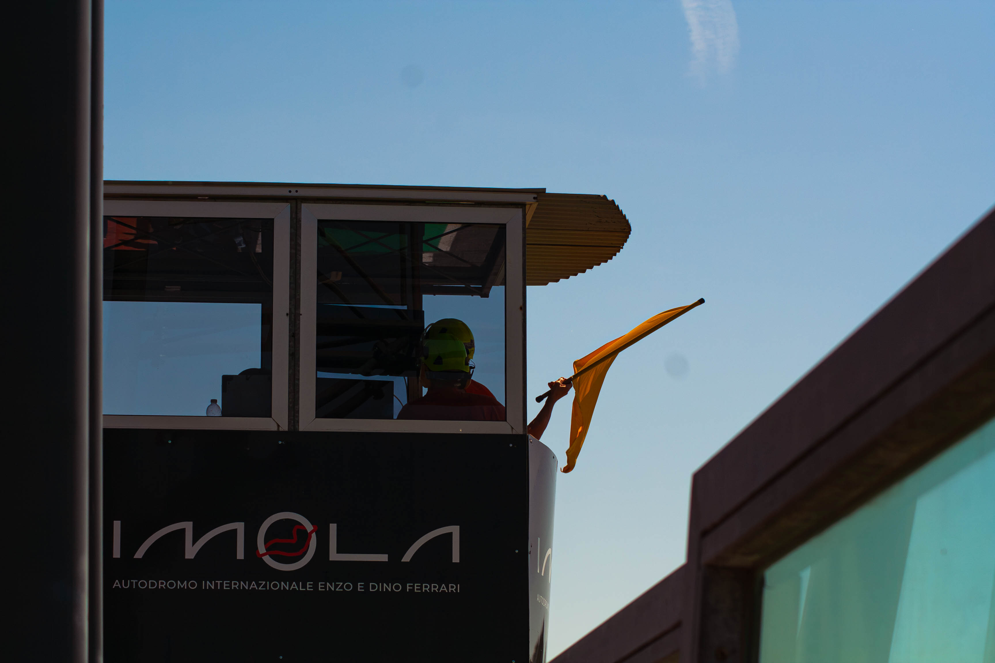 Track marshal waving a yellow flag from the observation post at Imola Circuit