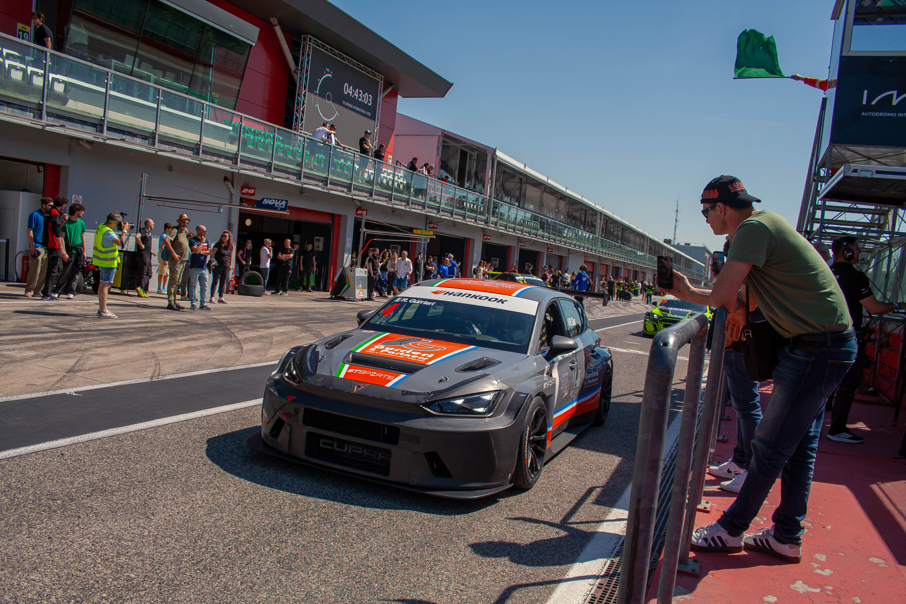 Cupra Leon Competición TCR driving down the pit lane with pit wall spectators and green flag at Imola Circuit